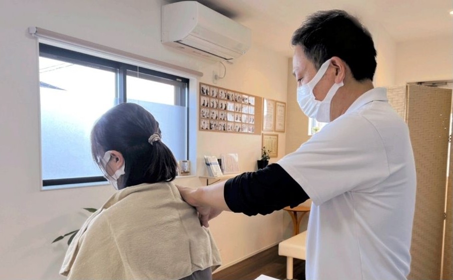 40女性患者様の四十肩の施術を、はる整体院の院長が後ろ側から施術している写真